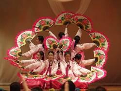 両手に扇を持ち、宮廷衣装を身にまとった生徒たちが韓国の伝統舞踊「プチェチュム」を披露している写真