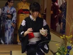 和室で茶道部の女子高生が着物をきて住民の参加者たちにお点前を披露している写真