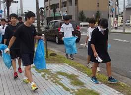 生徒たちが青いごみ袋を手に通学路やなじみの場所を巡って清掃している写真