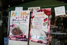 市場の一角にたてられた「大学生の自慢料理コンテスト」の看板があり近畿大学の生徒たちが出店しているが模擬店の写真