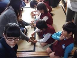 茶碗に入った抹茶を泡立てている園児と茶碗をおさえてサポートしている茶道部の女子生徒の写真