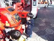 大きな消防車を間近で見れて、ワクワクにしている小さな男の子の写真