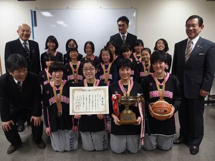 表彰状と優勝カップ、バスケットボールを持つ「パイレーツミニバスケットボールクラブ」の選手15人と市関係者の写真
