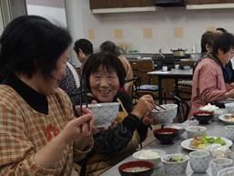 手前で2人の年配の女性が談笑しながら食事している写真