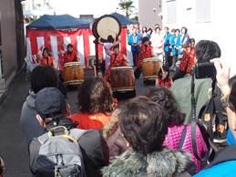 大太鼓を叩く1人と小太鼓を叩くオレンジ色の服を着た5人による和太鼓演奏の写真