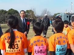 オレンジのユニフォームを着た子供たちが市長から激励を受けている時の写真