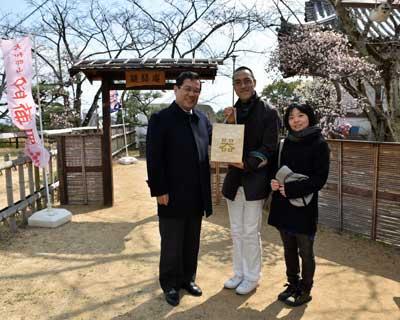 神社の境内の様な広場で、市長と記念品を贈呈された夫婦の10,000人目の来場者記念の写真