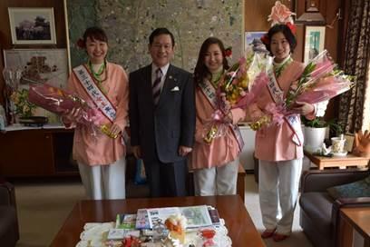 市長と花束を持つ、桃色の古代服を着た3人の女性の写真
