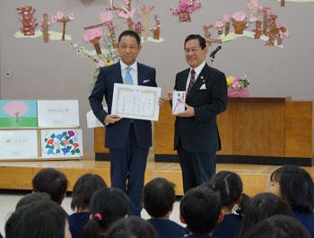 寄贈式の様子幼稚園の講堂で園児の前で絵本の贈呈式を行っている市長と支配人の様子の写真