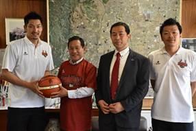 市長室で地元のプロバスケットボールチームの代表と選手2名と市長がバスケットボールを持っている様子の記念写真