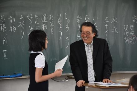 黒板の前で女子小学生と談笑している特別講師の先生の様子の写真