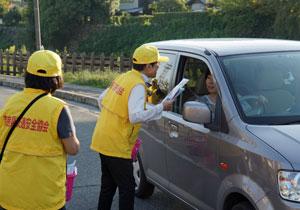 黄色いウェアを着た人がドライバーに話しかけている写真