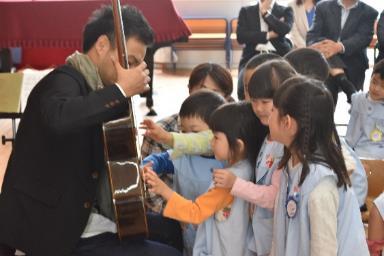 園児たちが大萩康司さんに集まりギターに触る写真
