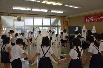 パネルが展示される部屋で生徒たちが手をつなぎ大きな輪になっている写真
