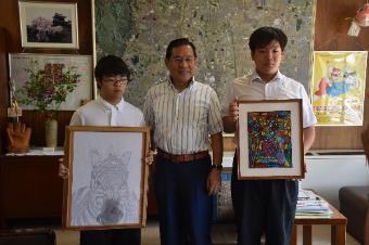 特別支援学校の2人が描きあげた作品を市長と並んで披露している様子の写真
