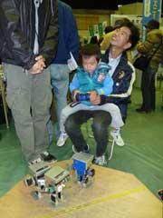 ラジコンを操作する子供を膝に乗せている男性の写真
