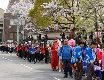 青い法被を着た人々が桜の下にいる写真