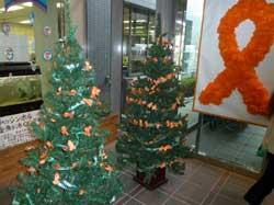 「すこやか21フェア」で屋外に展示されたクリスマスツリーにオレンジリボンが装飾されている写真
