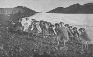 笠をかぶり杖をついた10数名が砂利の足場の上でこちらを見ている、大正後期頃のモノクロ写真