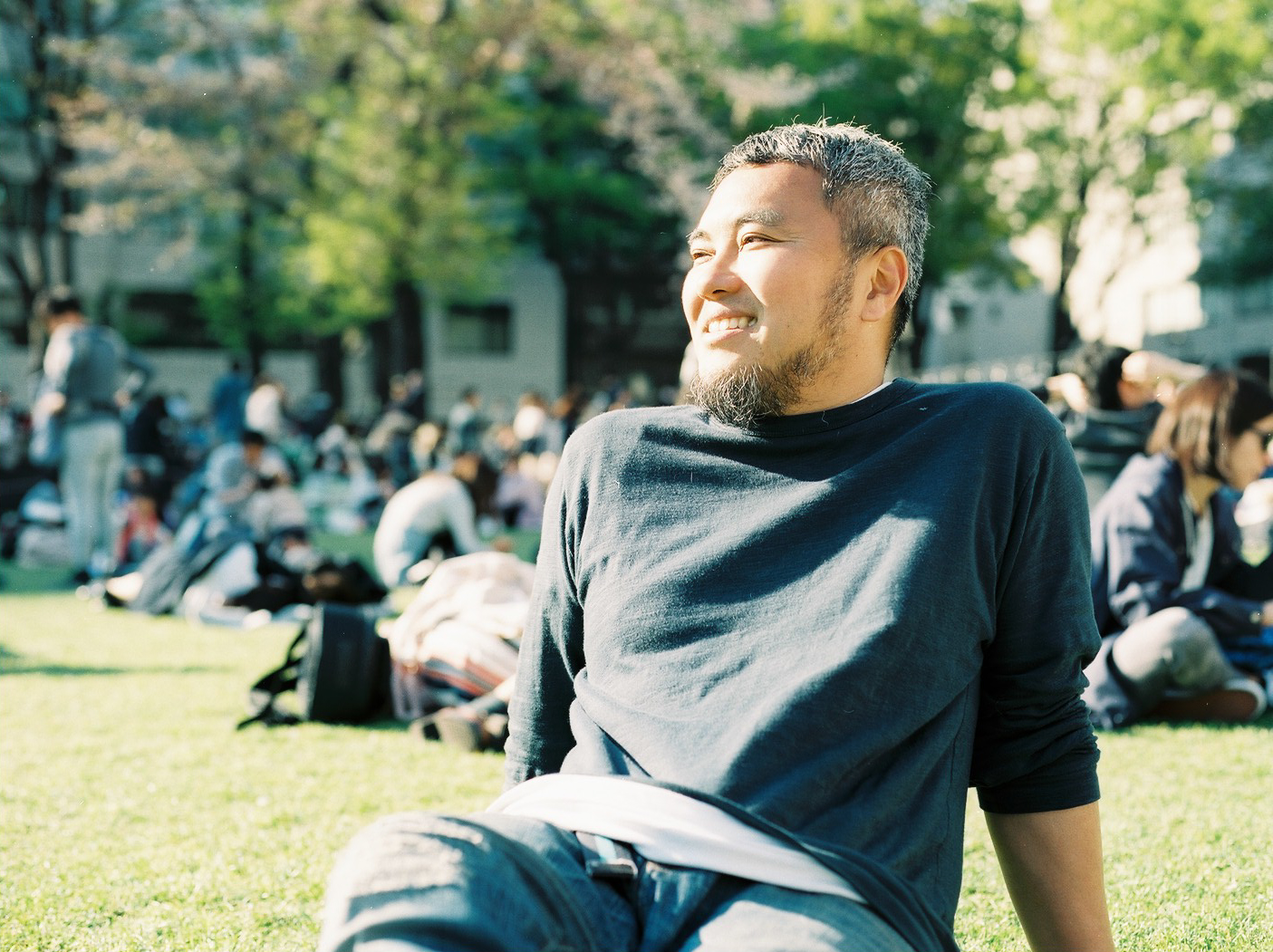 講師の青木純氏が芝生の上に座って空を眺めている。