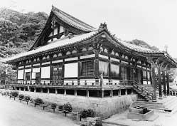 山を背景に、石垣の上に建てられた瓦葺きの金剛山寺本堂の外観を収めた写真