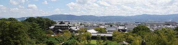 大和郡山城天守台から法印郭側の眺望をおさめた写真。城址会館の向こうに奈良の市街地やそれを囲む山々が見える