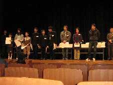 舞台上で表彰状を手に横に並んで立つ入賞者の人々の写真