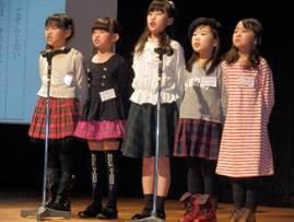 壇上で横に並んで暗唱発表をしている女の子5人のグループの写真