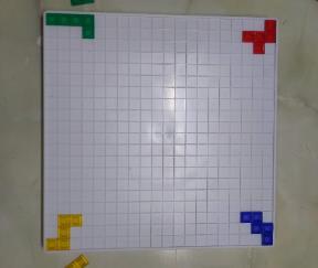 白いボードの四隅に各プレイヤーが最初のパーツを配置したブロックスの盤面の写真