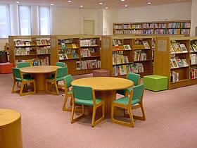 ピンク色のカーペットと丸テーブル、椅子が並んだ大和郡山市立図書館の内観写真