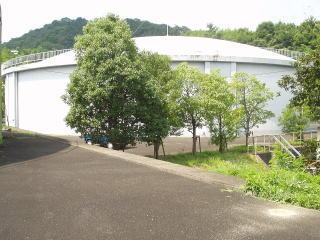 木々に囲まれて立つ、円筒に丸い屋根の形をした矢田山第4配水池の建物の写真