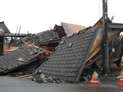 建物部分が完全に潰れて倒壊している瓦屋根のある住宅の写真