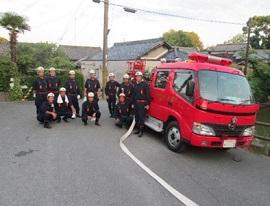 屋外で整列する消防団員と消防車の写真