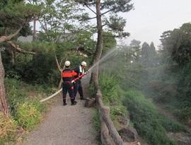 森で放水訓練をする消防団員たちの写真