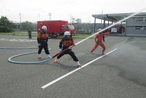 駐車場で放水訓練をする消防団員を近くで撮った写真