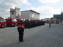 屋外で整列する消防団員と敬礼する消防団員の写真
