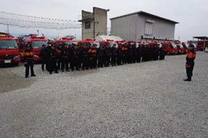 屋外で整列する消防団員と挨拶する消防団員の写真