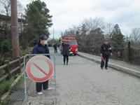 道路で警備する消防団員と消防車と看板の写真