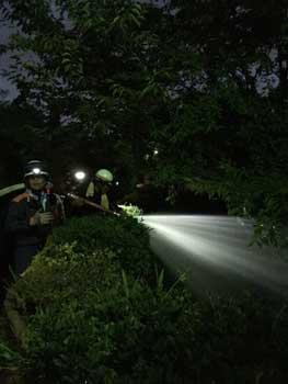 夜間の河原で見回りをしている消防団員の写真