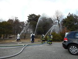 屋外にて放水訓練する消防団員たちの写真